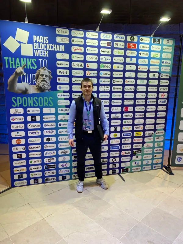 Paul Dupont in front of the Paris Blockchain Week sponsor wall